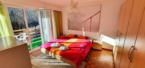 a bedroom with a red bed and a large window at Perle de Leysin in Leysin