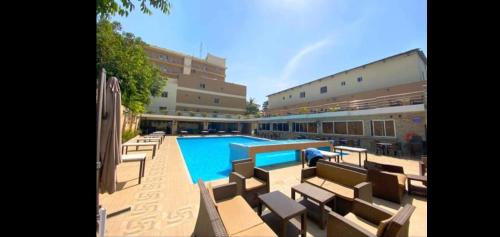 a swimming pool with chairs and a building at Tahir Guest Palace in Kano