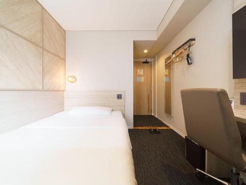 a hotel room with a bed and a chair at Super Hotel Midosujisen Esaka in Suita