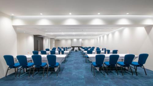 a conference room with long tables and blue chairs at Holiday Inn Express Mexico Aeropuerto by IHG in Mexico City