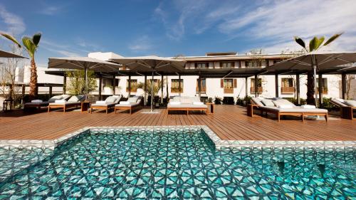 a pool with chairs and umbrellas next to a house at Cartesiano Boutique & Wellness Hotel in Puebla