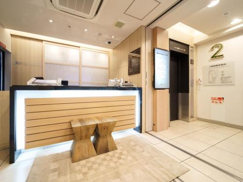 a reception desk with a bench in a room at Super Hotel Midosujisen Esaka in Suita
