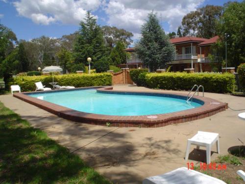 una piscina en un patio con una casa en Coachmans Rest Motor Lodge, en Coonabarabran