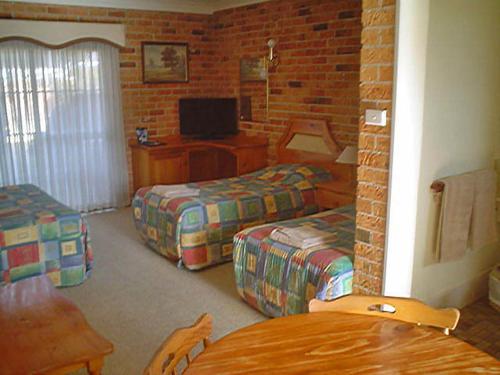 a room with two beds and a television in it at Coachmans Rest Motor Lodge in Coonabarabran
