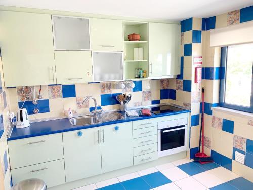 a kitchen with white cabinets and blue and white tiles at Penthouse 160sqm wide Terraces Pool view & private Hot Tub & Parking in Albufeira