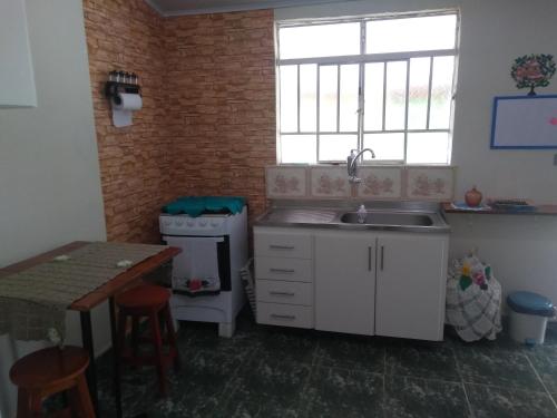 a kitchen with a sink and a table and a window at Casinha azul in Sapucaí-Mirim