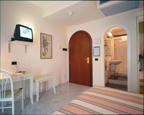 een kamer met een deur, een bureau en een televisie bij Hotel Elena in Recco