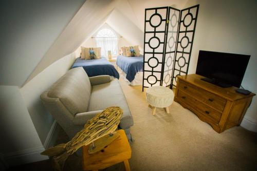 a attic room with a couch and a bed and a television at Tranquil Days Guest House ---- Arbour Garden in Stratford