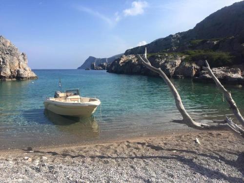 a boat sitting in the water on a beach at TO VOTSALO-beach side studios & taverna in Karpathos Town