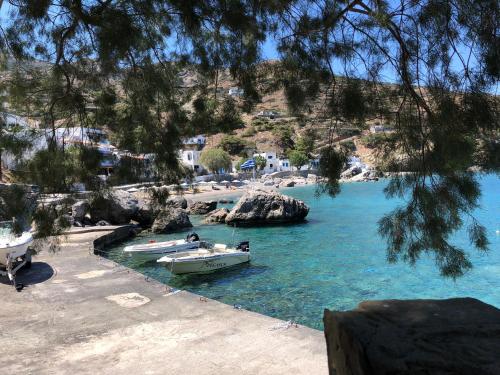 two boats are docked in the water on a beach at TO VOTSALO-beach side studios & taverna in Karpathos Town