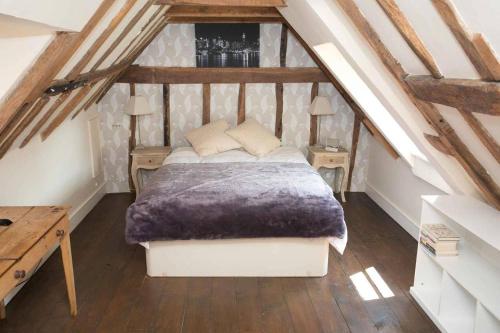 sypialnia na poddaszu z łóżkiem i drewnianą podłogą w obiekcie Medieval Town House - Walled Garden Sleeps 8 w mieście Rye