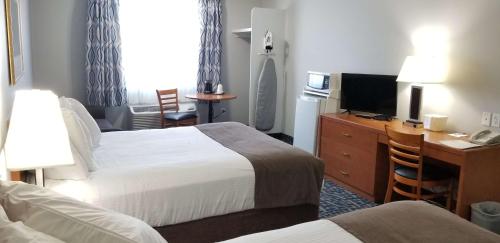 a hotel room with two beds and a desk and a television at SureStay Plus Hotel by Best Western Lethbridge in Lethbridge