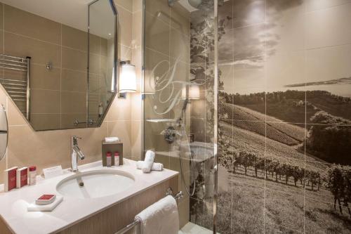 ein Bad mit einem Waschbecken und einer Dusche in der Unterkunft Hôtel & Spa Les Sept Fontaines Best Western Premier in Tournus