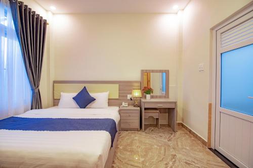 a bedroom with a bed and a desk and a mirror at Khanh Uyen 1 Hotel in Da Lat