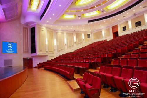 an empty auditorium with red chairs and a stage at GUOCE Beijing Capital Airport Hotel & Convention Center in Shunyi