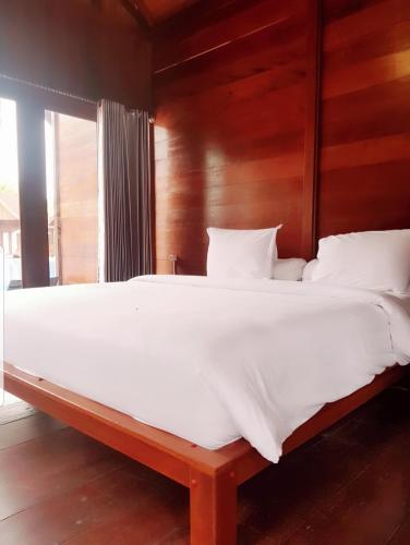 a bedroom with a large white bed with a wooden headboard at Korpak Villa & Resort Raja Ampat in Saonek