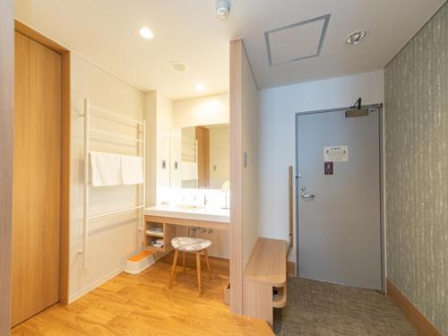 a bathroom with a sink and a shower and a desk at Kyukamura Myoko in Myoko