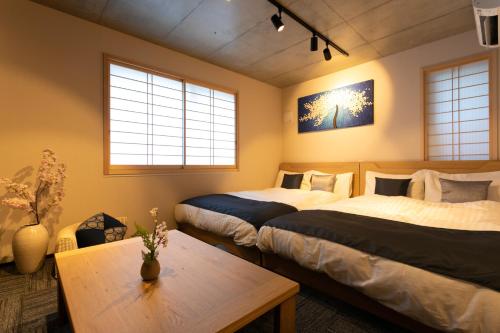 two beds in a room with a table and two windows at Sakura Stay Otorii in Tokyo