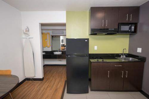 a kitchen with brown cabinets and a black refrigerator at Studio 6-Tyler, TX in Tyler