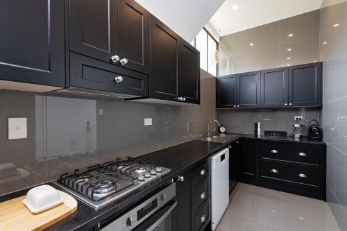 a kitchen with black cabinets and a stove top oven at Pirralilla Estate Adelaide Hills in Aldgate
