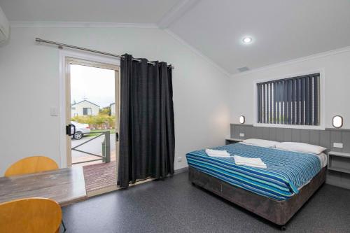 um quarto com uma cama e uma porta de vidro deslizante em Karrinyup Waters Resort em Perth