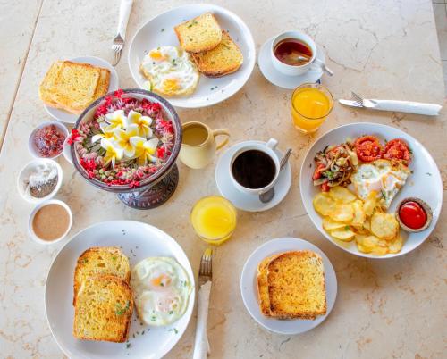 een tafel met borden met ontbijtproducten en drankjes bij Baliku Dive Resort in Amed