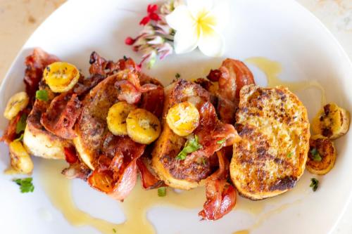 een bord met ontbijtproducten zoals wentelteefjes en spek bij Baliku Dive Resort in Amed