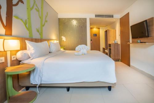 a bedroom with a large bed with a teddy bear on it at Grand Livio Kuta Hotel in Legian
