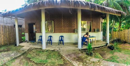 a woman sitting at a table in front of a house at SHUKRAN Apartelle in Siquijor