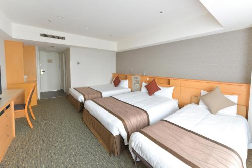 a hotel room with three beds and a desk at Narita Tobu Hotel Airport in Narita