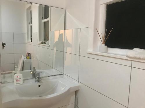 a white bathroom with a sink and a window at Auckland One Tree Hill Cody suite in Auckland