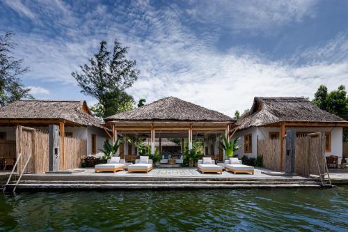 a villa on the water with chairs and a dock at Chi-Bu Riverside in Nhơn Trạch