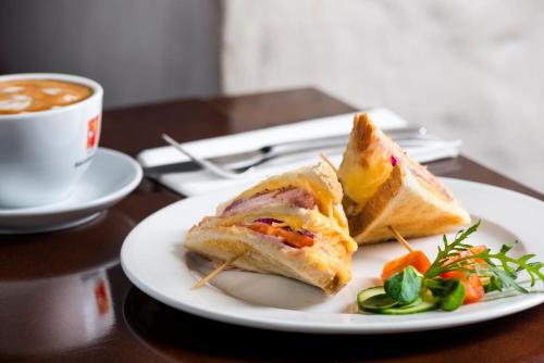 a white plate with a sandwich and a cup of coffee at Aparthotel Stare Miasto in Kraków