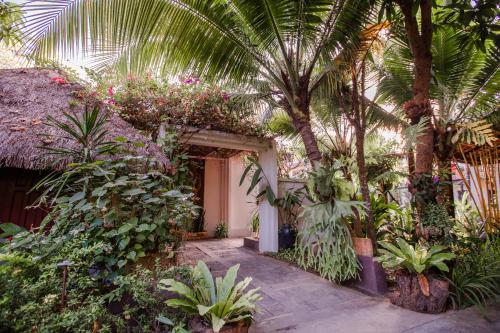 a garden with palm trees and plants in front of a house at The Sanctuary Villa Battambang in Battambang
