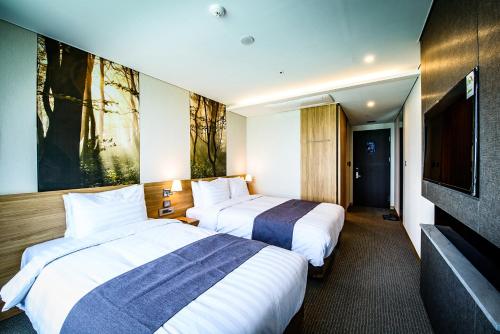 a hotel room with two beds and a flat screen tv at Utop Ubless Hotel Jeju in Jeju