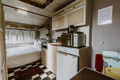 małą kuchnię z łóżkiem i małą lodówką w obiekcie The Stables w mieście Langebaan