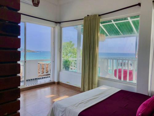 a bedroom with a bed and two large windows at Surf Bar Mirissa in Mirissa