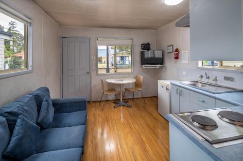 a living room with a blue couch and a table at Ingenia Holidays Nepean River in Emu Plains