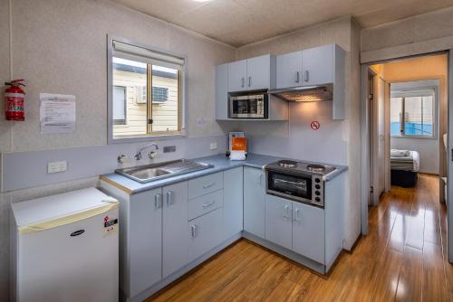 a kitchen with white cabinets and a sink at Ingenia Holidays Nepean River in Emu Plains