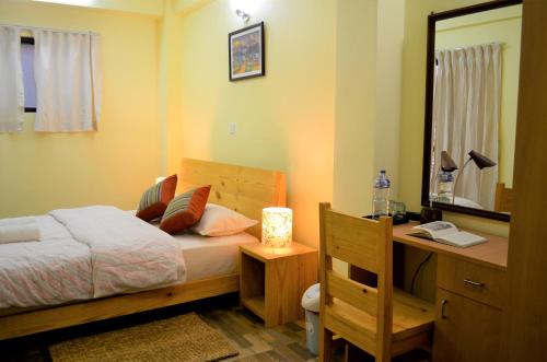 1 dormitorio con cama, escritorio y espejo en Tanani Newa Home -Dhaulagiri, en Pātan