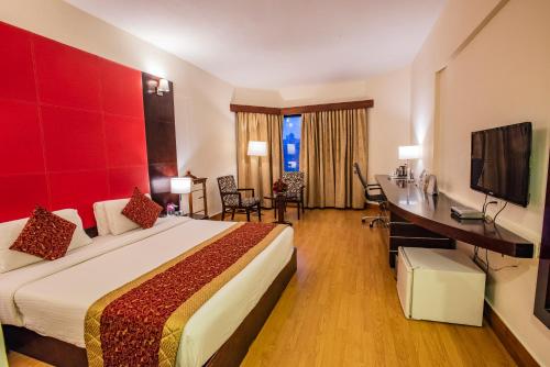 a hotel room with a large bed and a desk at The South Park Hotel in Trivandrum