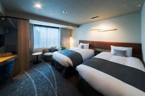 a hotel room with two beds and a desk at Hotel Granvia Osaka-JR Hotel Group in Osaka