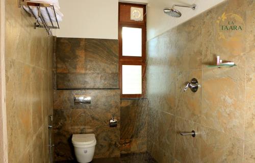 a bathroom with a toilet and a window at La Taara - Feel Home in Auroville