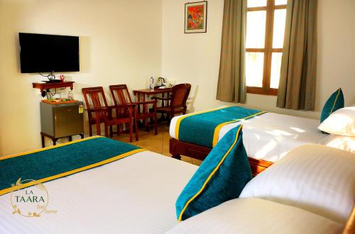 a hotel room with two beds and a television at La Taara - Feel Home in Auroville