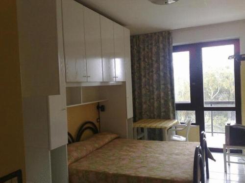 Residence Nettuno في كامبومارينو: غرفة نوم بسرير ونافذة وطاولة