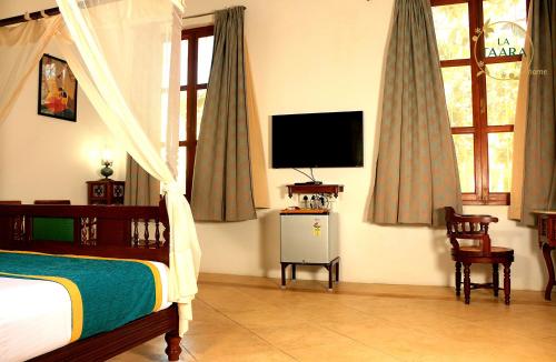 a bedroom with a bed and a flat screen tv at La Taara - Feel Home in Auroville