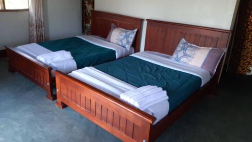 two twin beds in a room at Tangi Safari Lodge in Pakwach East