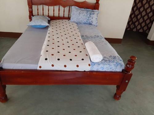 a wooden bed with polka dot sheets and pillows at Tangi Safari Lodge in Pakwach East