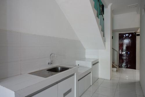 a white kitchen with a sink and a hallway at RedDoorz Hostel near Kota Lama Semarang in Semarang