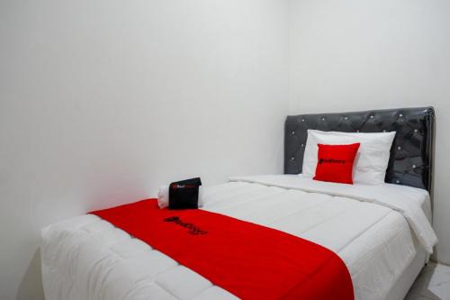 a bed with a red blanket on top of it at RedDoorz Hostel near Kota Lama Semarang in Semarang